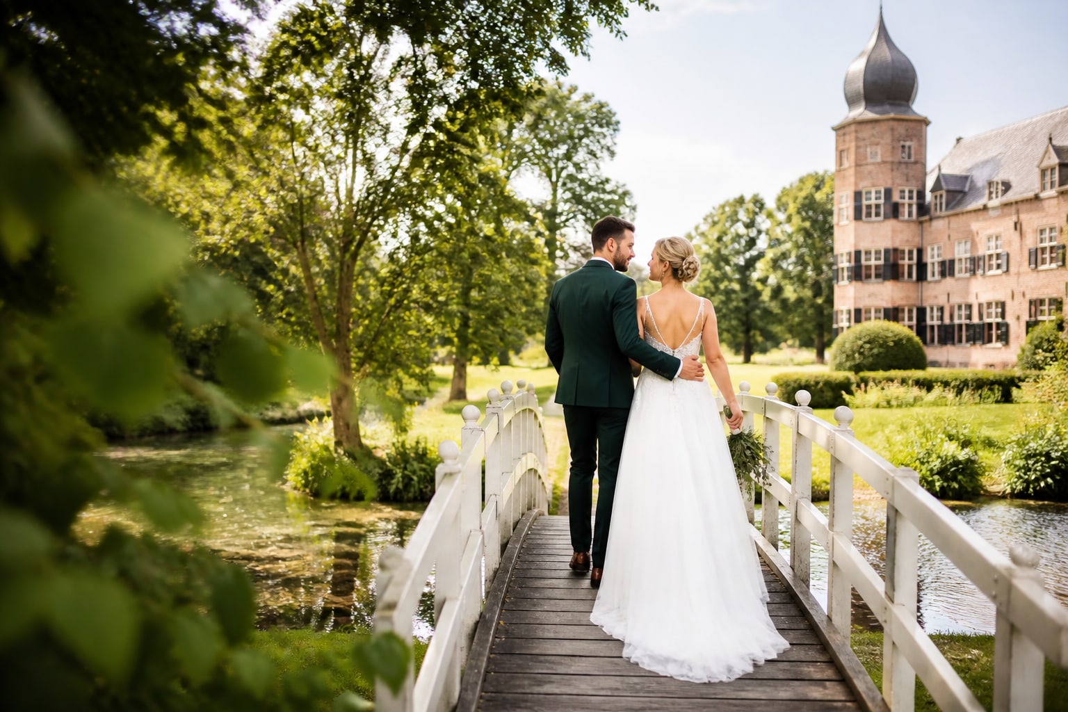 Het bruidspaar loopt over een witte brug naar een kasteel