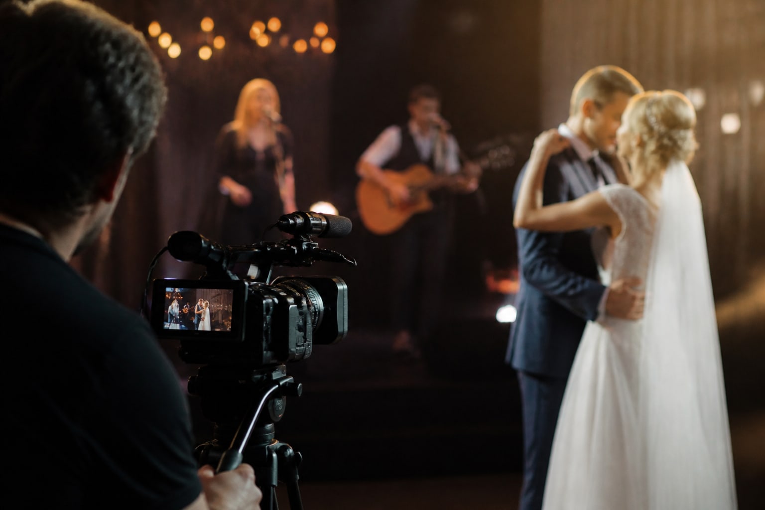 Een videograaf filmt de eerste dans terwijl een band live speelt