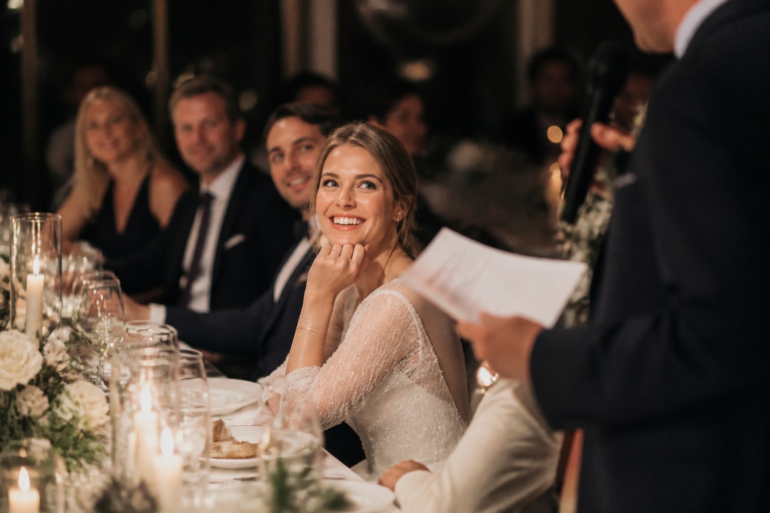 De bruid lacht aan tafel om een speech tijdens het diner