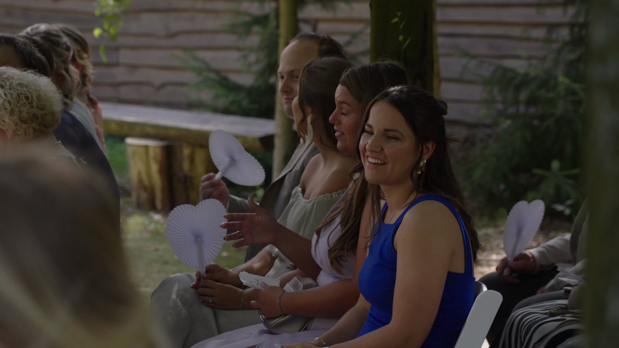 Gasten kijken glimlachend naar de ceremonie in het bos, uit de trouwfilm van Romy en Marijn